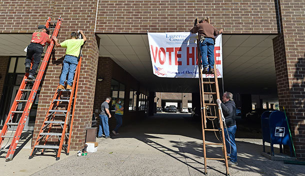 Luzerne County staff raise a voting banner.
