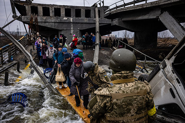 Ukrainian evacuees cross a destroyed bridge outside of Kyiv in March.