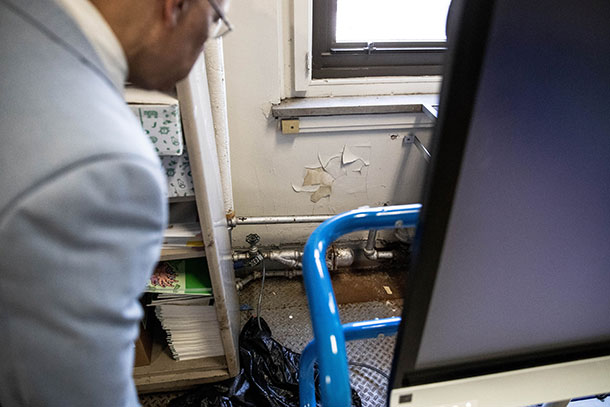 Hughes inspects a water-damaged bathroom wall inside one of Philadelphia’s public schools.