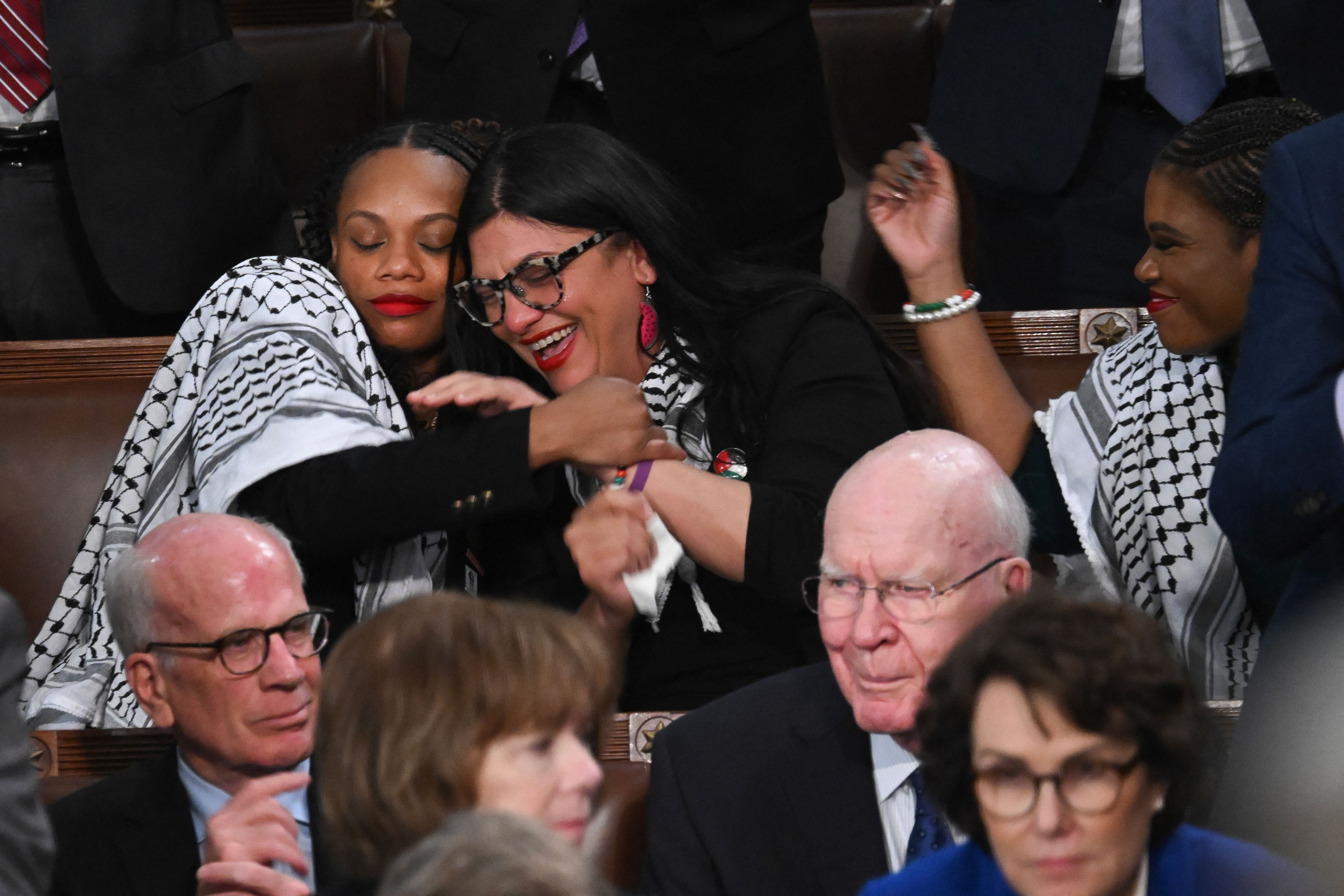 US Representative Summer Lee, Democrat of Pennsylvania, embraces US Representative Rashida Tlaib, Democrat of Michigan, as US President Joe Biden delivers the State of the Union address in the House Chamber of the US Capitol in Washington, D.C., on March 7, 2024.