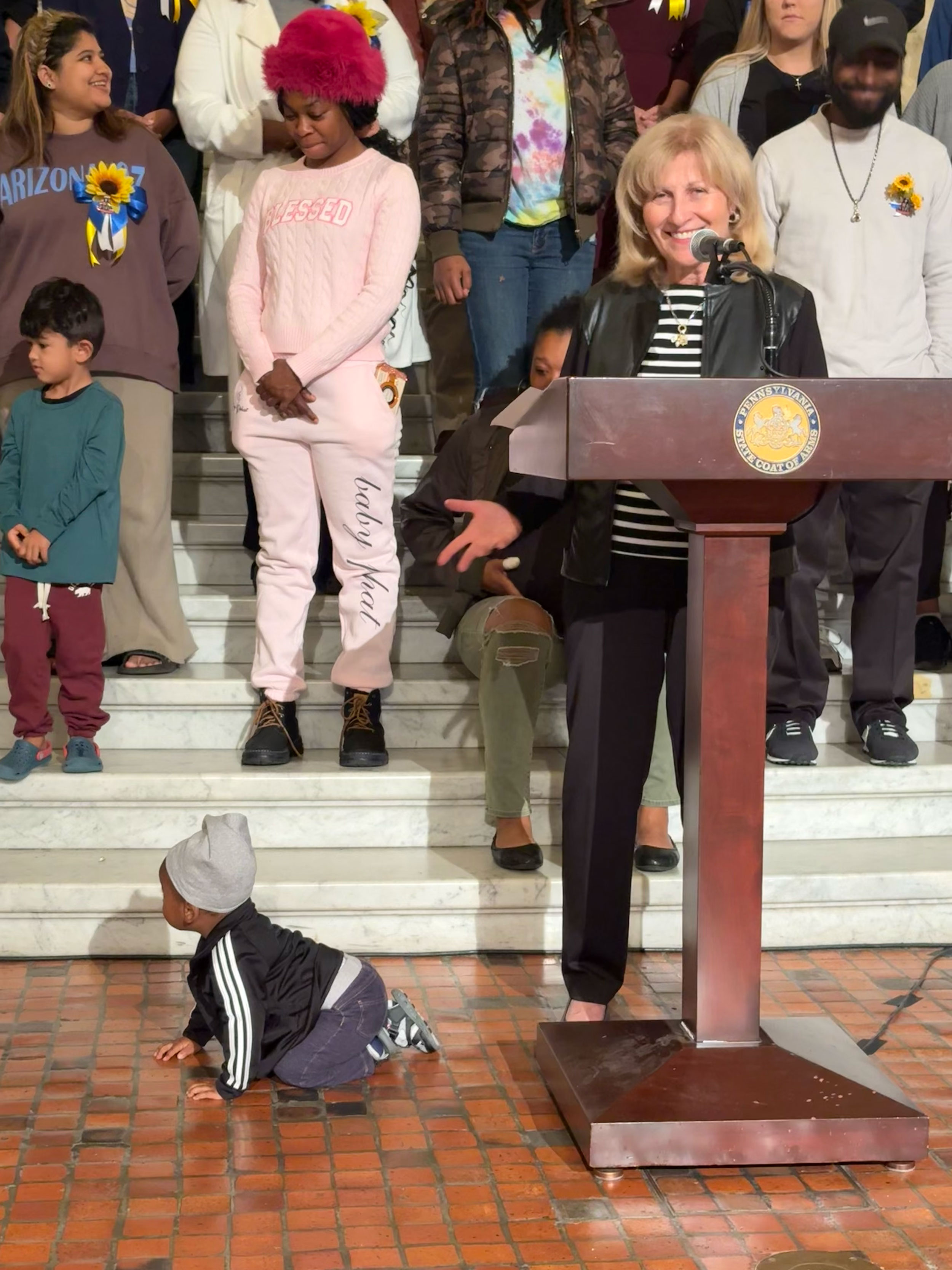 State Sen. Judy Schwank is greeted by a baby at the podium while speaking about Head Start. 
